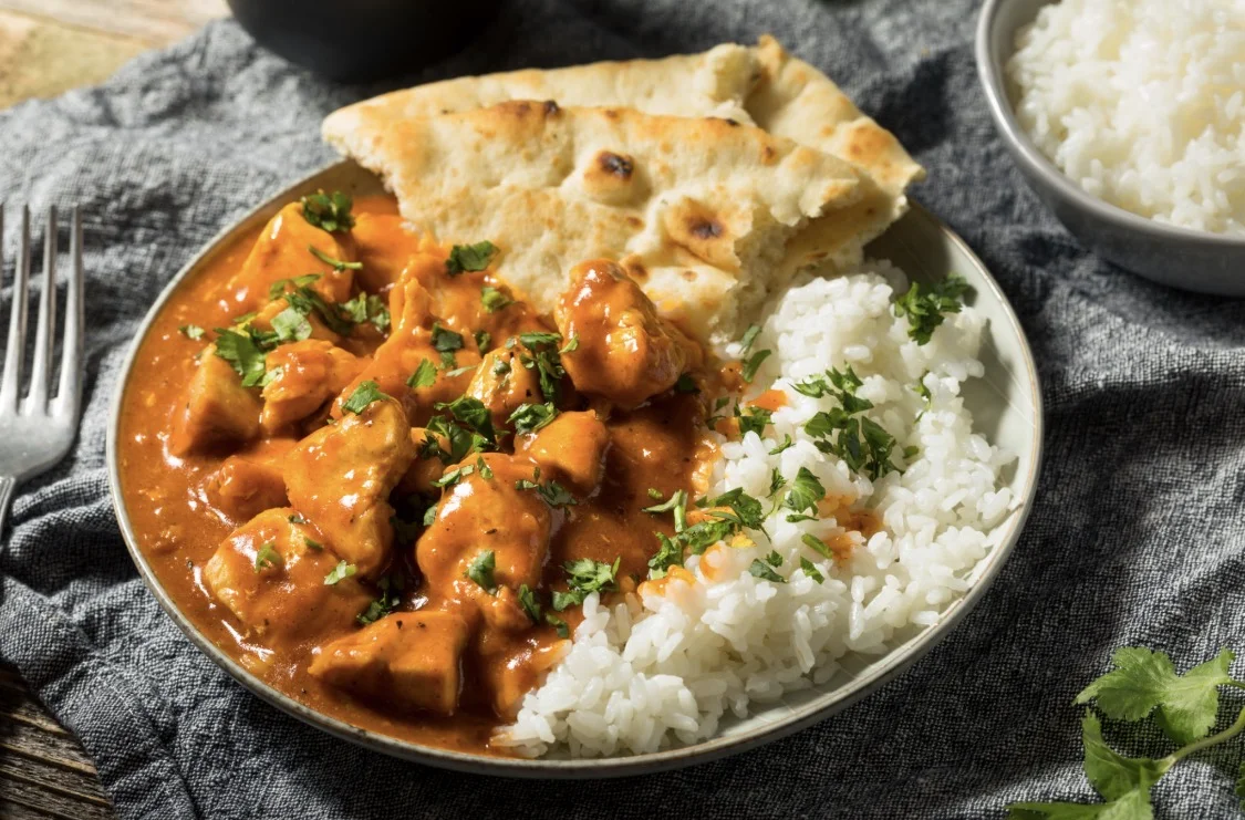 Creamy butter chicken served with rice and naan